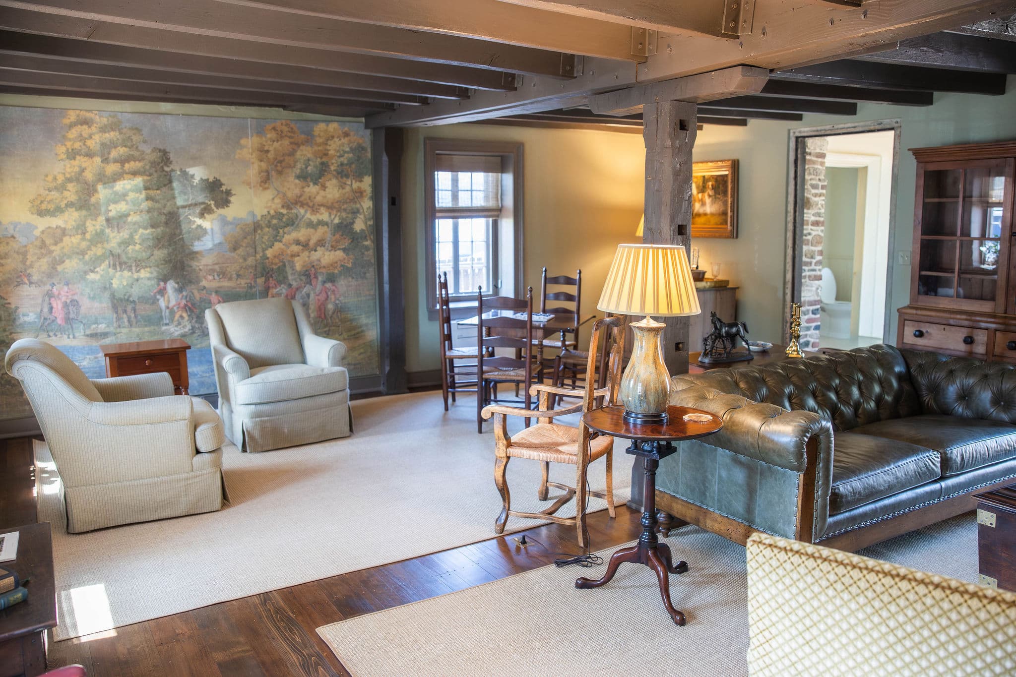 Cozy living room featuring a mural, vintage furniture, and warm lighting.